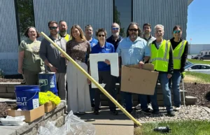 Bishop-Community-service-care-crew1 Group of volunteers posing with cleanup gear outside a modern building.