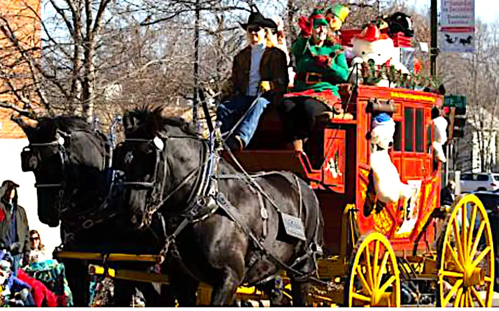Bishop-Community-service-care-crew2 Two black horses pull a bright red parade float with yellow wheels as costumed riders wave to spectators