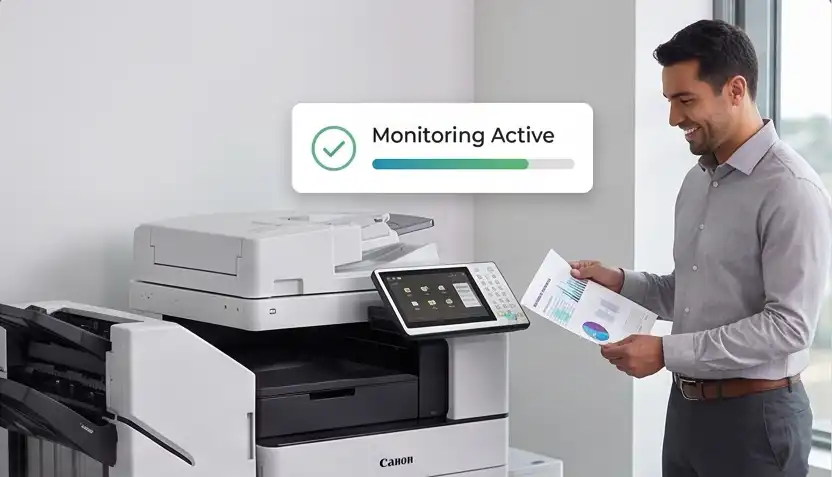 Man in business attire stands beside a Canon multifunction printer, reviewing reports as a 'Monitoring Active' status badge with a green progress bar appears above.